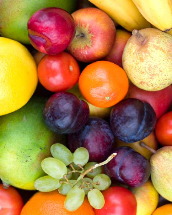 A pile of fruit including apples, grapes and plums.