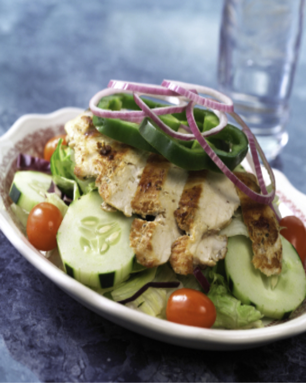 A salad with chicken and tomatoes on top of it.